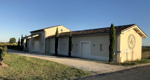 Bâtiment du Château La Rose Vircoulon vu depuis l’entrée, avec logo peint sur le mur et allée gravillonnée